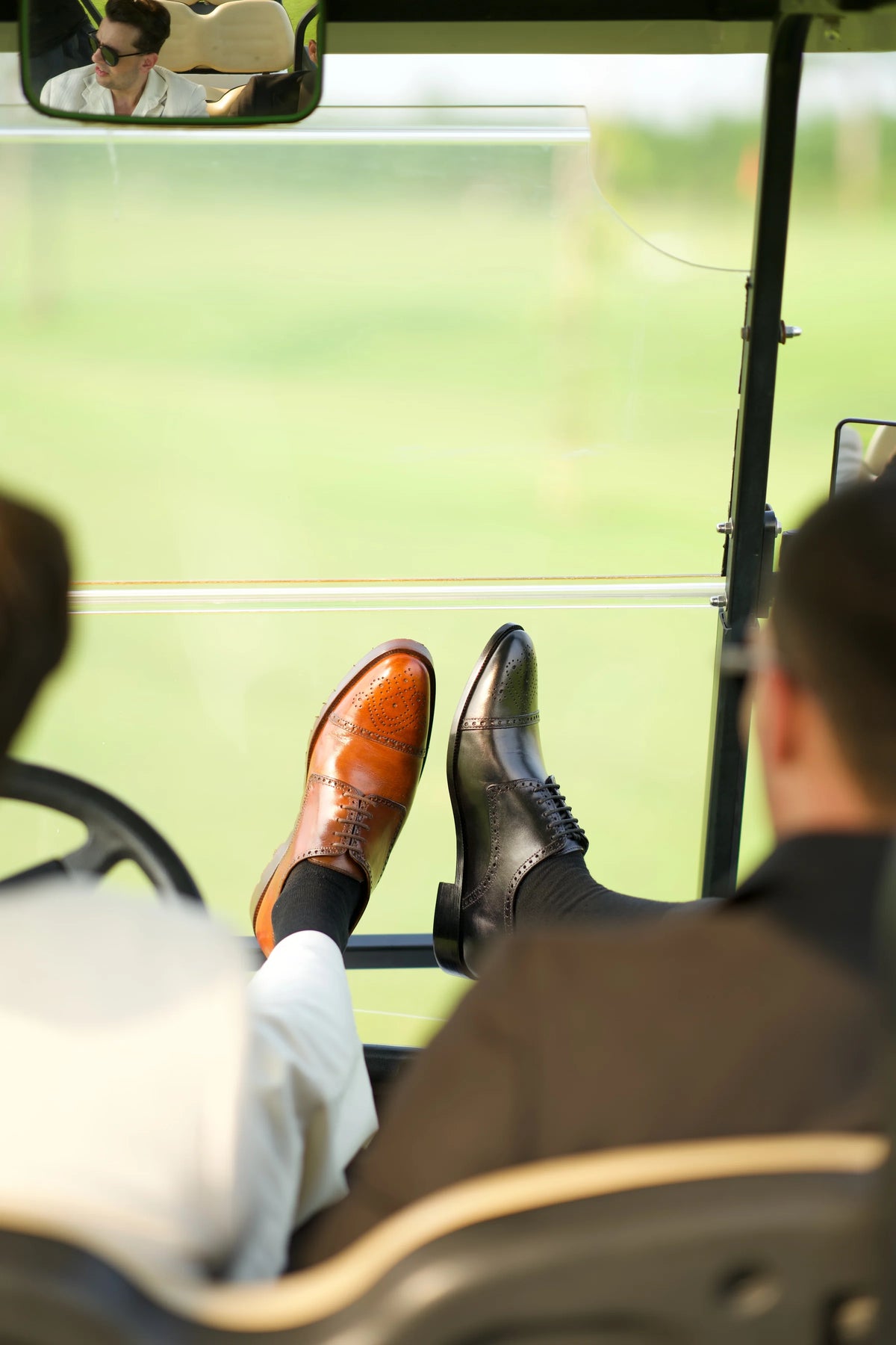 Tan and black Cueřo brogues resting on the dashboard of a golf cart