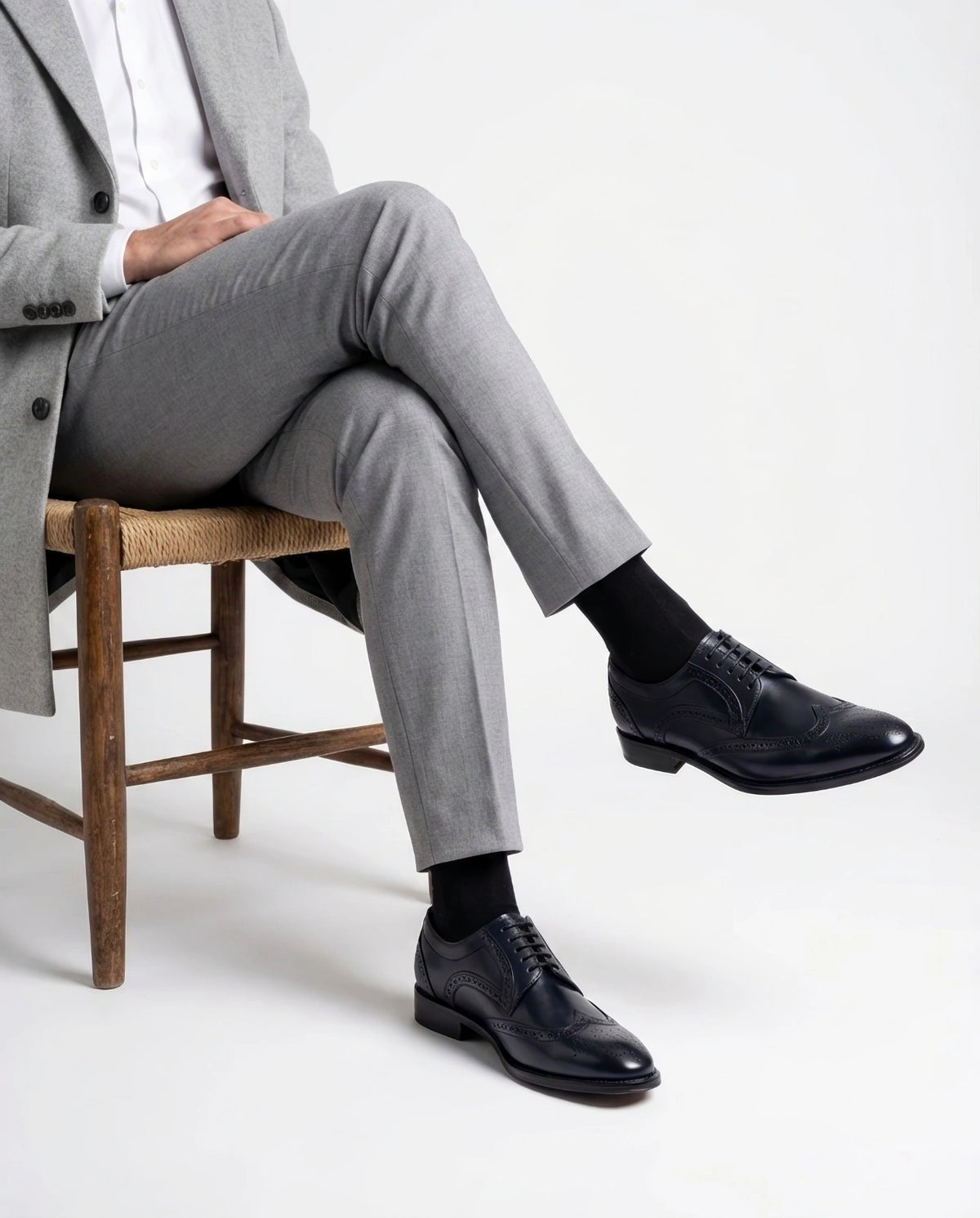 Leonardo Blue lace-up shoes styled with Grey tailored outfit in seated model pose showcasing modern gentleman luxury aesthetic