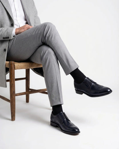 Leonardo Blue lace-up shoes styled with Grey tailored outfit in seated model pose showcasing modern gentleman luxury aesthetic