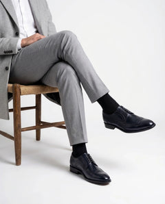 Leonardo Blue lace-up shoes styled with Grey tailored outfit in seated model pose showcasing modern gentleman luxury aesthetic