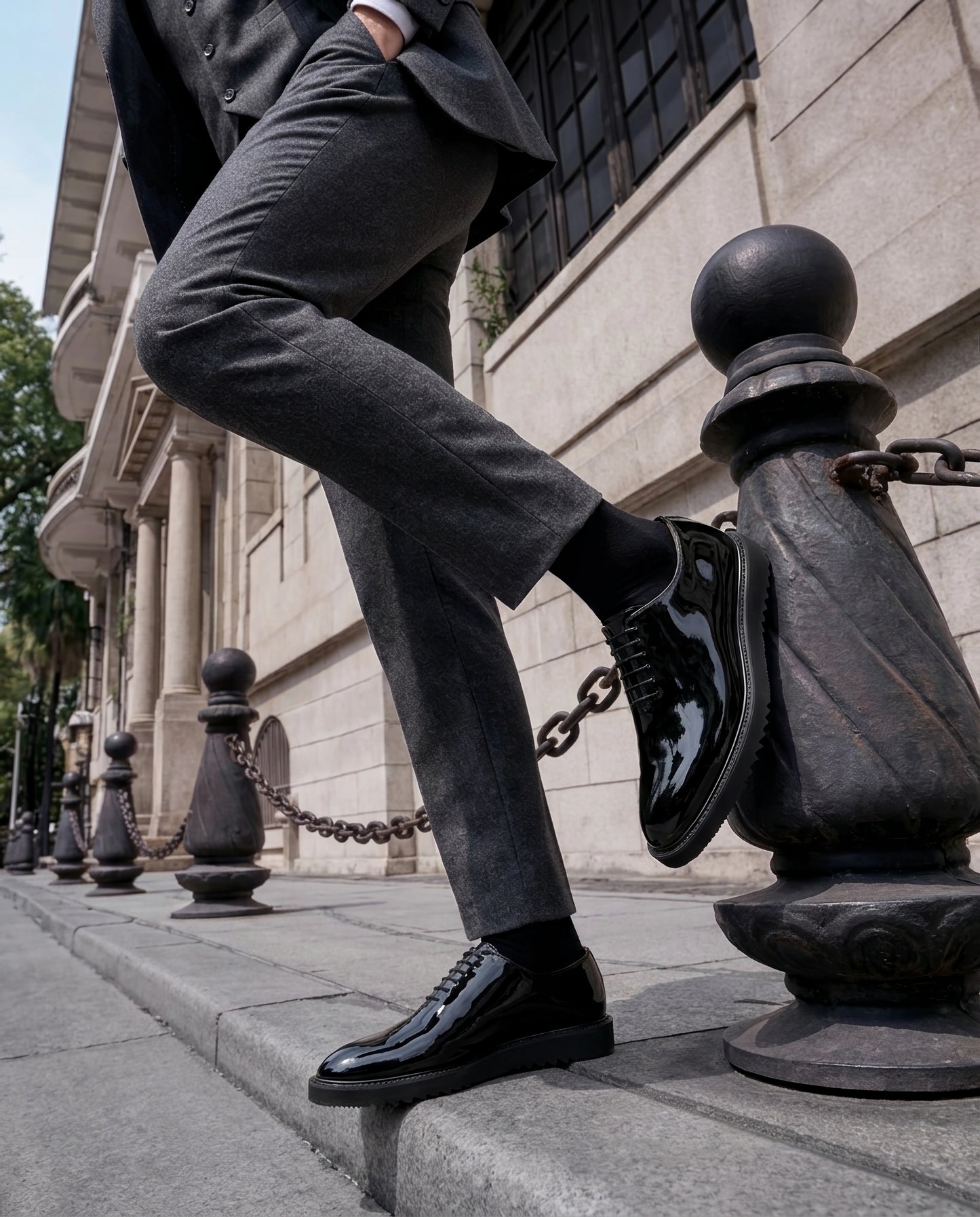 The Vance Cueřo Grand Atelier luxury men’s formal dress shoes worn in a lifestyle shot stepping on a street bollard chain in an urban setting