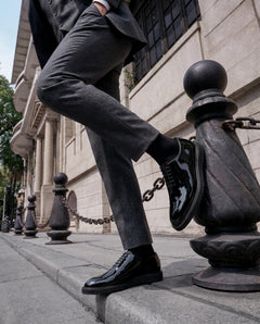 The Vance Cueřo Grand Atelier luxury men’s formal dress shoes worn in a lifestyle shot stepping on a street bollard chain in an urban setting