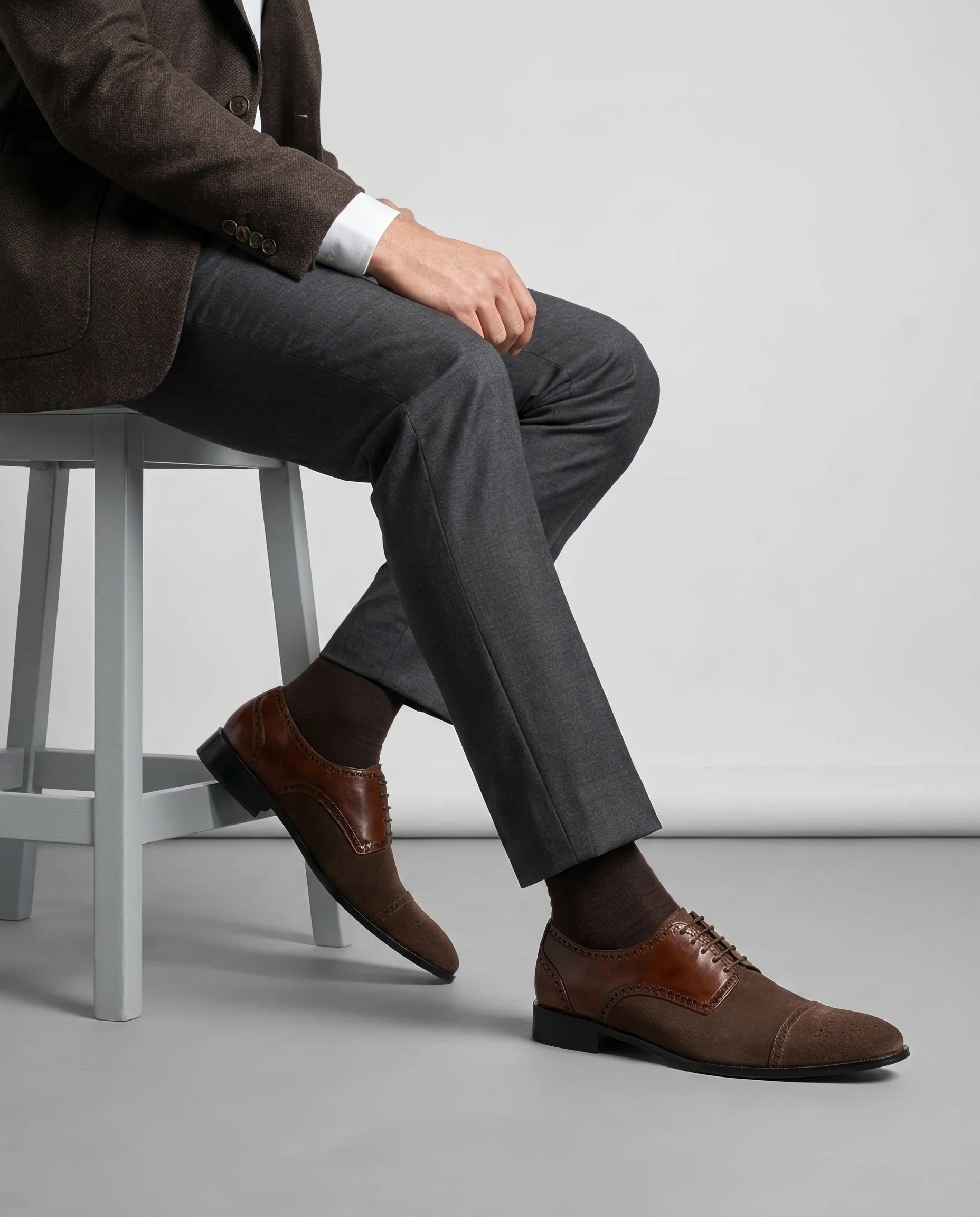 Lifestyle shot of Duke’s Plush lace-up oxford shoes worn with tailored menswear, seated pose showcasing elegant formal styling and premium finish