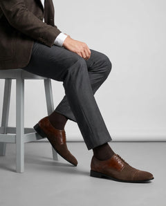 Lifestyle shot of Duke’s Plush lace-up oxford shoes worn with tailored menswear, seated pose showcasing elegant formal styling and premium finish