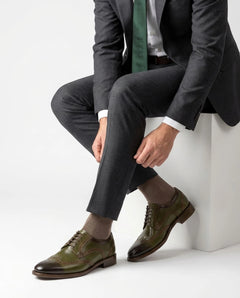 Lanx brogue formal lace-up shoes styled with grey suit in seated model pose showcasing bold luxury menswear elegance