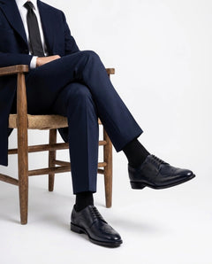 Leonardo Blue navy leather oxford dress shoes worn with tailored navy suit in a luxury studio fashion setting