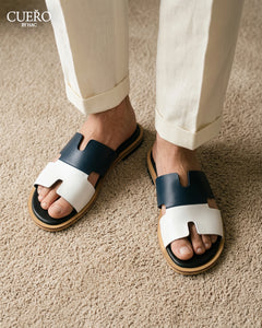 Designer blue leather slides photographed in modern editorial setting
