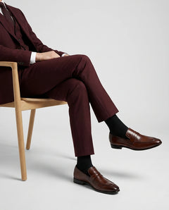 Noble Line Mehrun brown leather loafers worn with maroon tailored suit in a luxury editorial seated pose on wooden chair