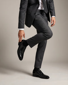 Person wearing a gray suit and Regal black shoes on a plain background