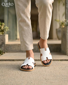 Designer white leather slides photographed in modern editorial setting