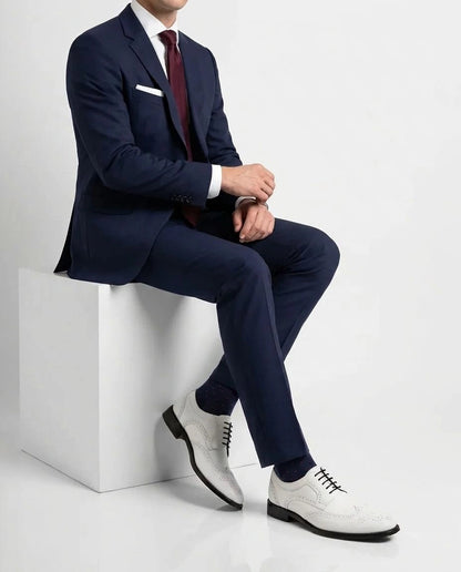Welby White brogue lace-up shoes styled with formal outfit in seated lifestyle pose showcasing elegance and modern luxury menswear