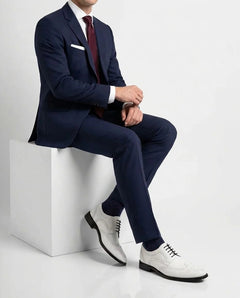 Welby White brogue lace-up shoes styled with formal outfit in seated lifestyle pose showcasing elegance and modern luxury menswear